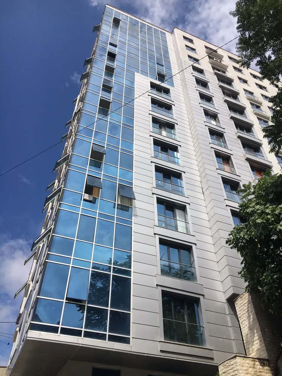 Rozehill Residence binasının ağaçlar arasından sokaktan görünümü